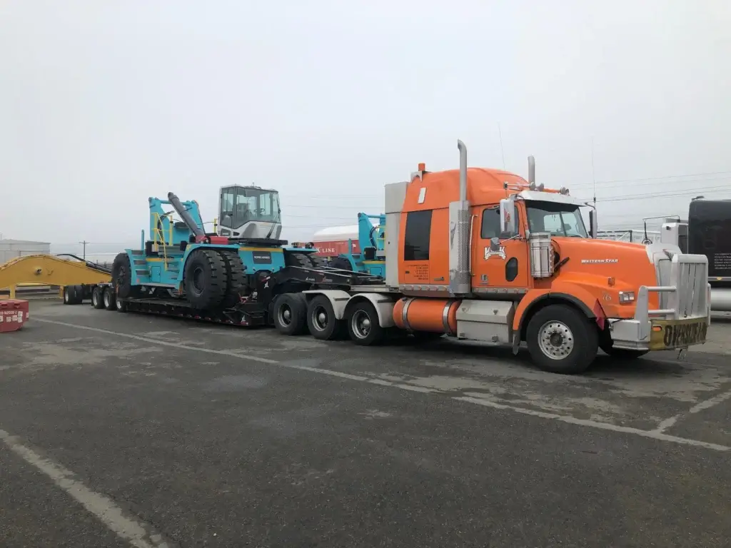Oversize flatbed truck hauling heavy construction equipment