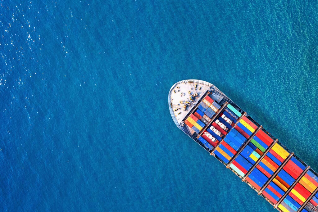 Aerial view of a cargo ship carrying colorful shipping containers across blue ocean water